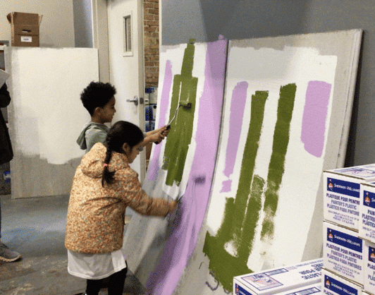 Kindergarten students in Chicago test paint by rolling it onto boards